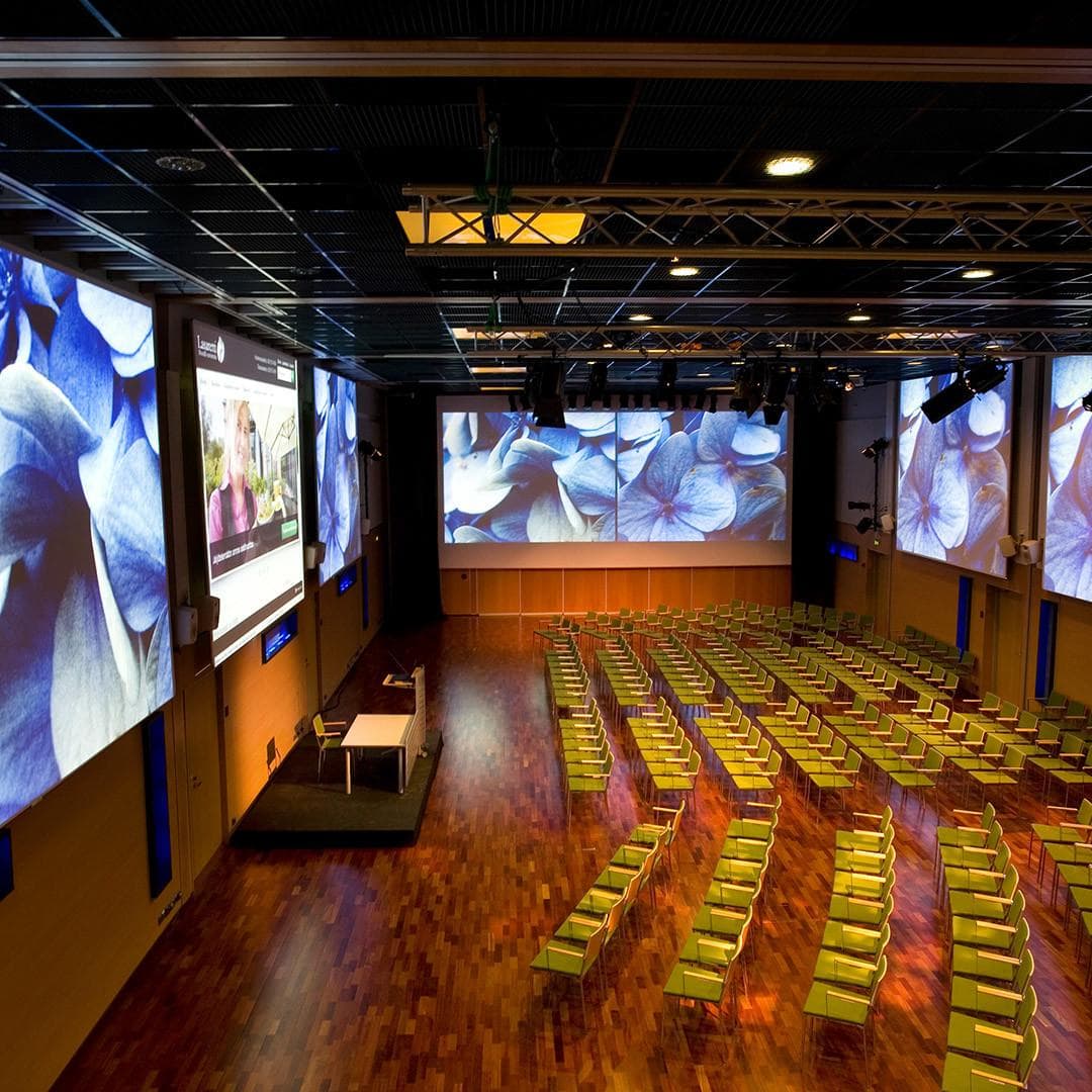 Chairs arranged to the lecture form in the Aurora Hall, where a spectacular performance is projected on the screens.